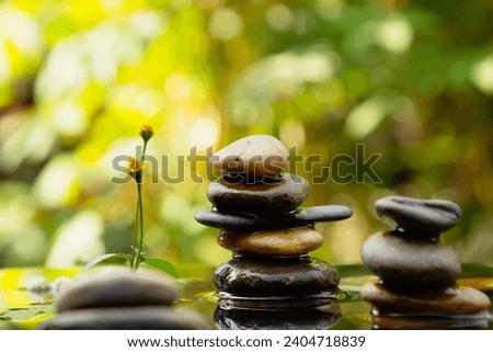 Balanced rocks pyramid with water drops surround it on water with Golden light natural peace concept