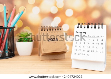 White February 2024 desk calendar on wooden table with gold light bokeh background. New Year Concept. Royalty-Free Stock Photo #2404724029