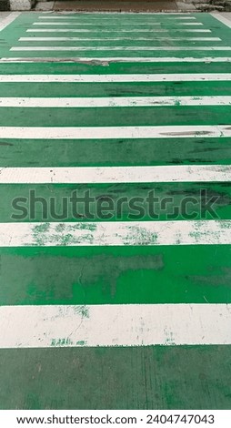 Green and white zebra crossing as a traffic crossing sign on a public road