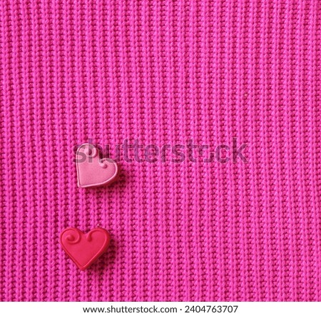Two gingerbread hearts are n a soft pink knitted background