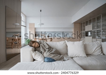 Frustrated young woman lying on couch at home suffering from heartbreaking divorce. Girl feeling bad, apathy hiding from society in loneliness solitude. Mental disorder, anhedonia, stress, sleepiness. Royalty-Free Stock Photo #2404776329