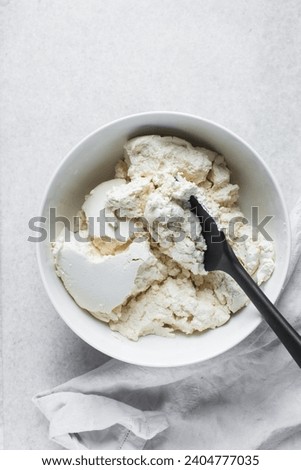 Strained Greek yogurt in a white ceramic bowl, process of making Greek yogurt, strained thick yogurt in white mixing bowl Royalty-Free Stock Photo #2404777035
