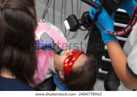 Female dentist, with the help of an assistant, photographs the patient's tooth. Concept of macrophotography of teeth in the dental office before and after treatment