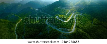 Top view from drone of mountain road in woods in a summer day.