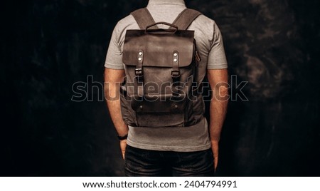 Man with stylish canvas backpack on dark background, back view. Close up