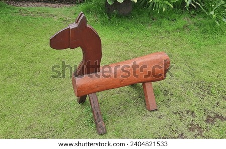 Wooden toy horse for children's play on green grass park.
