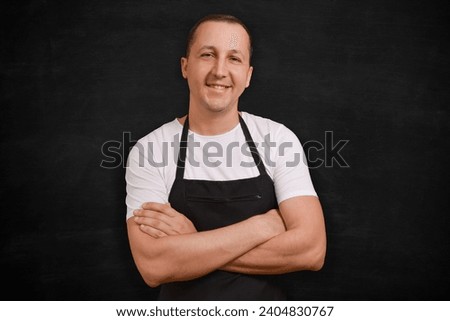Happy man chef in apron looking at camera on black background. Royalty-Free Stock Photo #2404830767
