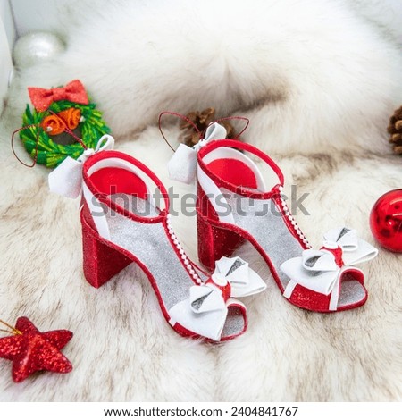 Lovely red toy-shoes for Mrs. Claus. Christmas tree ornaments. Glossy red sandals made of glitter foam decorated with huge white bows. White fir bg, ideas for New year gifts and decorations. Handmade.