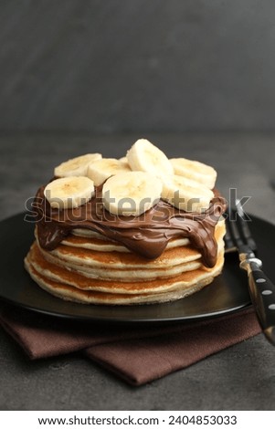 Tasty pancakes with chocolate spread and sliced banana served on gray table