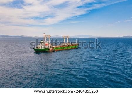 Bulk carrier ship anchored with pilot boat for crew change, aerial view Royalty-Free Stock Photo #2404853253