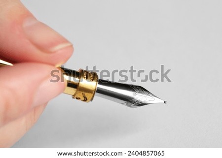 Woman with fountain pen above white paper, closeup