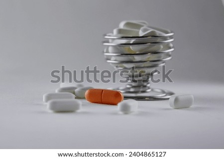Carrot-colored pills lie among white pills on the table. White pills in a metal mold. Medical preparations, nutritional supplements, biologically active food additives, vitamins, minerals, probiotics.