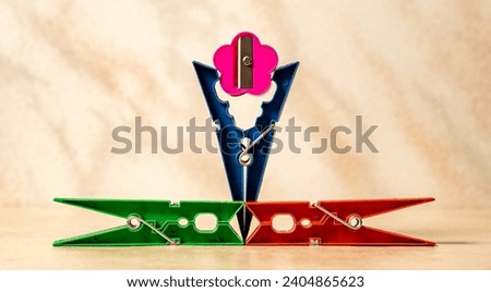 The great pinch.  Abstract image of cloth pegs and a pencil sharpener being pinched.