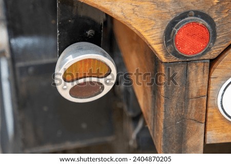 ancient round close-up rear light of an old car with reflector and indicator on a wooden car woody van