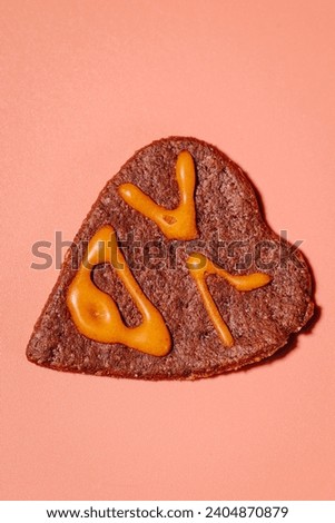 Colorful heart-shaped cookie-gingerbread on a pink background for Valentine's Day. Heart-shaped gingerbread on a pink background. Love and prosperity. Gingerbread with a frosted face.