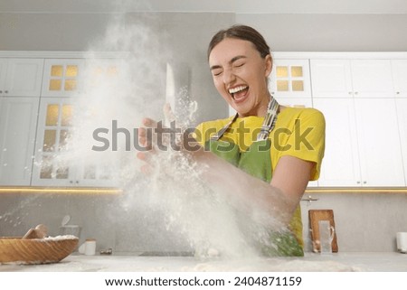 Funny woman clapping floury hands over messy table in kitchen Royalty-Free Stock Photo #2404871159