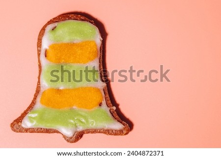 Colorful bell-shaped cookie-gingerbread on a pink background. Bell gingerbread on a pink background. Gingerbread with a frosted surface.