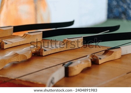 wooden bows with stretched string lie on stand ready for shooting at shooting range, sports shooting concept, outdoor activities, friendly competitions, corporate party, team building