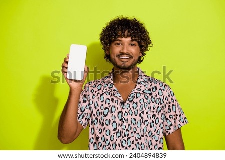 Photo portrait of handsome young guy hold white screen device dressed stylish pink leopard print outfit isolated on yellow color background