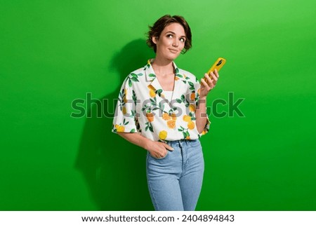 Photo of adorable cute girl wear stylish summer outfit hand hold modern device look banner empty space isolated on green color background