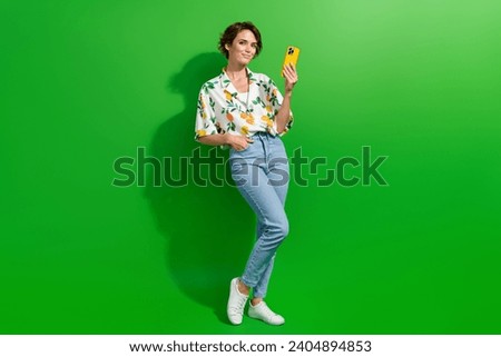 Full length size body photo of attractive young cute woman using smartphone browsing social medias isolated on green color background