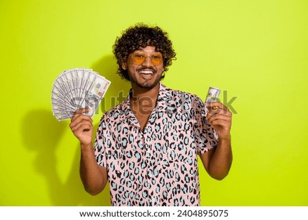 Photo portrait of handsome young guy hold dollars banknotes dressed stylish pink leopard print outfit isolated on yellow color background