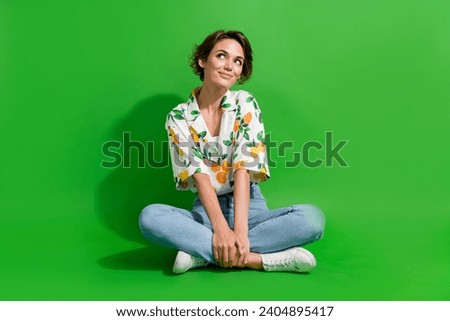 Full body photo of young woman sitting floor looking thoughtful wondered spend money on black friday isolated over green color background