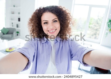 Photo of toothy adorable woman wear violet shirt recording video vlog showing home indoors apartment kitchen