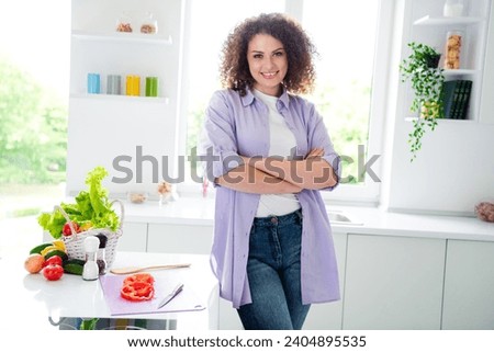 Photo of shiny positive woman wear violet shirt arms folded chopping red sweet fresh pepper preparing supper indoors apartment kitchen