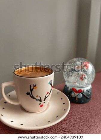 Greek coffee in a cup with a deer picture and a snow globe next to it