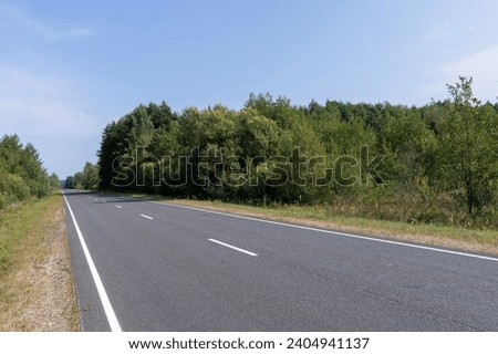 Narrow paved road for cars, part of a modern paved expressway for motor vehicles Royalty-Free Stock Photo #2404941137