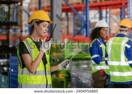 Professional Female Worker Wearing Hard Hat Checks Stock and Inventory with Digital Tablet Computer in the Retail Warehouse full of Shelves with Goods. People Working in Logistics Distribution Center