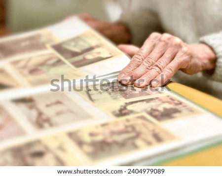 Hand of an elderly woman looking at a child's photo album
