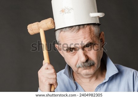 A crazy man with a saucepan on his head tries to find a thought with a hammer.