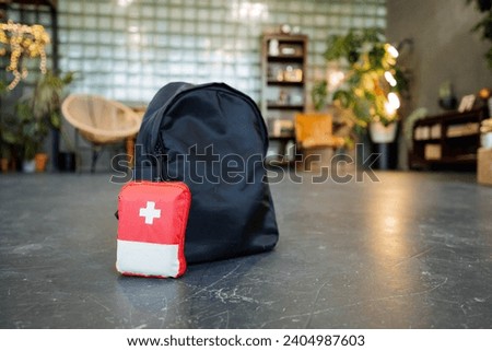 A first-aid kit is on the floor along with a backpack, travel medicines, and a black bag. High quality photo