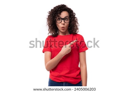 young surprised curly brunette woman dressed in a red t-shirt on a white background with copy space