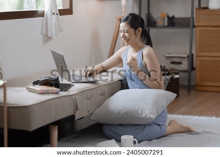 Happy and excited Asian women with laptop computer sitting on sofa at home.