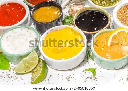 Assortment of different classic sauces and dips in sauceboats. Mayonnaise, ketchup, tartare, mustard, pesto, sour cream, barbecue sauces with spices, herbs, lemon Royalty-Free Stock Photo #2405010869