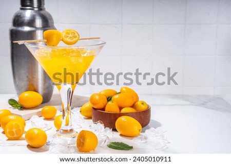Kumquat martini cocktail, non-alcohol mocktail, tropical citrus fruit drink in martini glass, with sliced and whole kumquat and mint on table background copy space Royalty-Free Stock Photo #2405010911