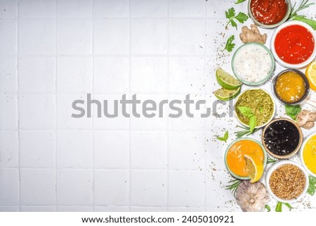 Assortment of different classic sauces and dips in sauceboats. Mayonnaise, ketchup, tartare, mustard, pesto, sour cream, barbecue sauces with spices, herbs, lemon Royalty-Free Stock Photo #2405010921