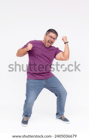 An ecstatic man celebrating by dancing around, overwhelmed with joy. Full body shot, isolated on a white background. Royalty-Free Stock Photo #2405036679