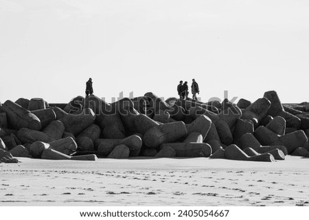 Black and white photo of unidentified people walking on a breakwater