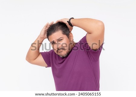 A egotistical man fixes his waxed hair trying to look cool, but looking funny instead. Wearing a purple waffle shirt. Half body photo isolated on white background. Royalty-Free Stock Photo #2405065155