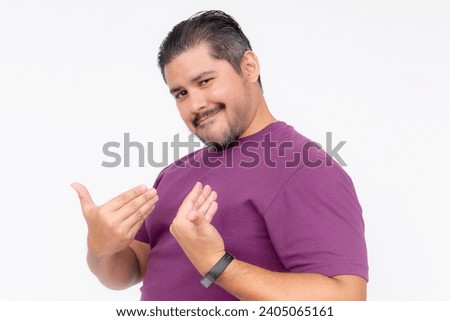 A cocky man points to himself bragging while looking smug. Wearing a purple waffle shirt. Half body photo isolated on white background. Royalty-Free Stock Photo #2405065161