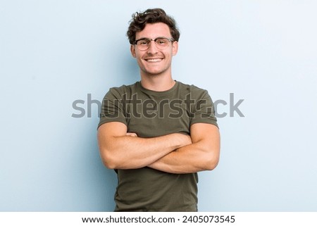 young handsome man looking like a happy, proud and satisfied achiever smiling with arms crossed Royalty-Free Stock Photo #2405073545