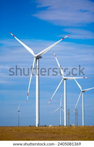 Fleet of power generators in motion. The blades of the wind farm rotate against the sky. The concept of extracting electricity from renewable sources. Wind turbine to generate electricity. Royalty-Free Stock Photo #2405081369