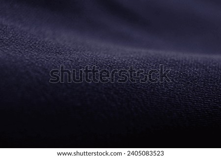 Photograph of a textured background made from a blue, navy blue cloth with a small mesh pattern and streaks, shiny.