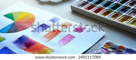 Artist's workplace. Art supplies brushes, paints, watercolors. Art studio. Drawing lessons. Creative workshop. Design place. Watercolor color wheel and palette. Color theory beginner hobby lessons. Royalty-Free Stock Photo #2405117089