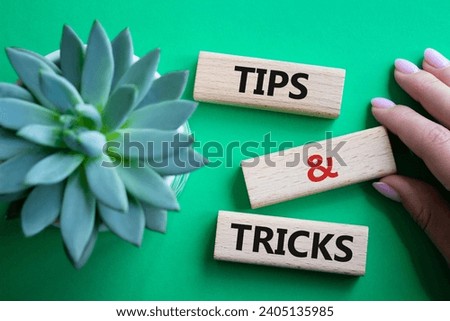 Tips and tricks symbol. Wooden blocks with words Tips and tricks. Beautiful green background with succulent plant. Businessman hand. Business concept and Tips and tricks. Copy space.