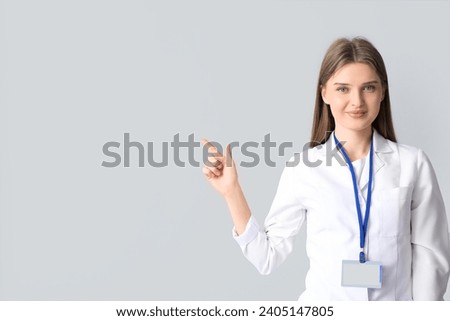 Beautiful doctor pointing at something on light background